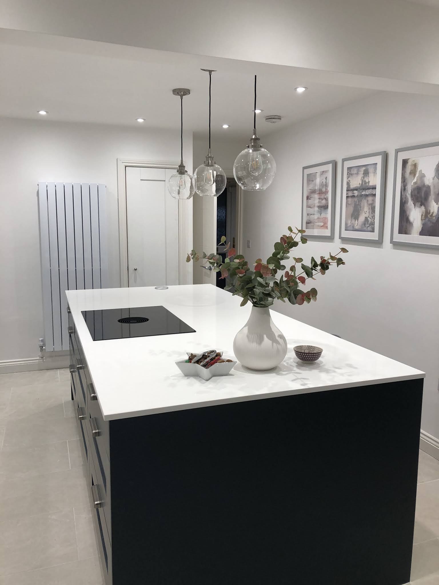 A new kitchen island lit by three glass pendant lights and recessed downlights