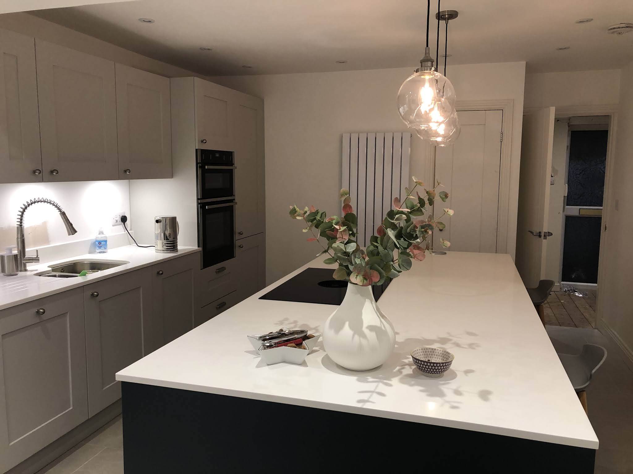 The same kitchen from the other end, with under-cabinet lights and downlights
