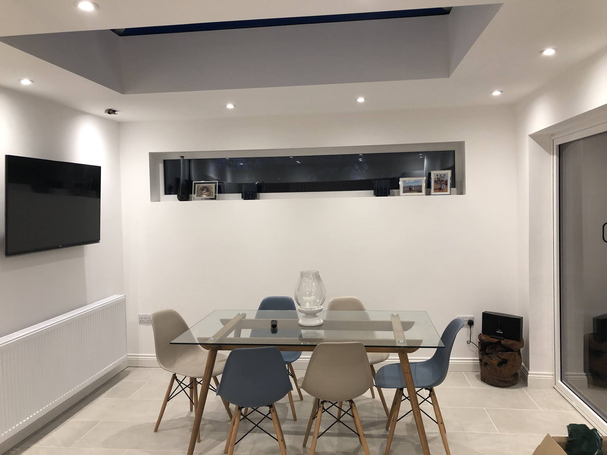 A dining area in a new extension with downlights and a lit feature shelf