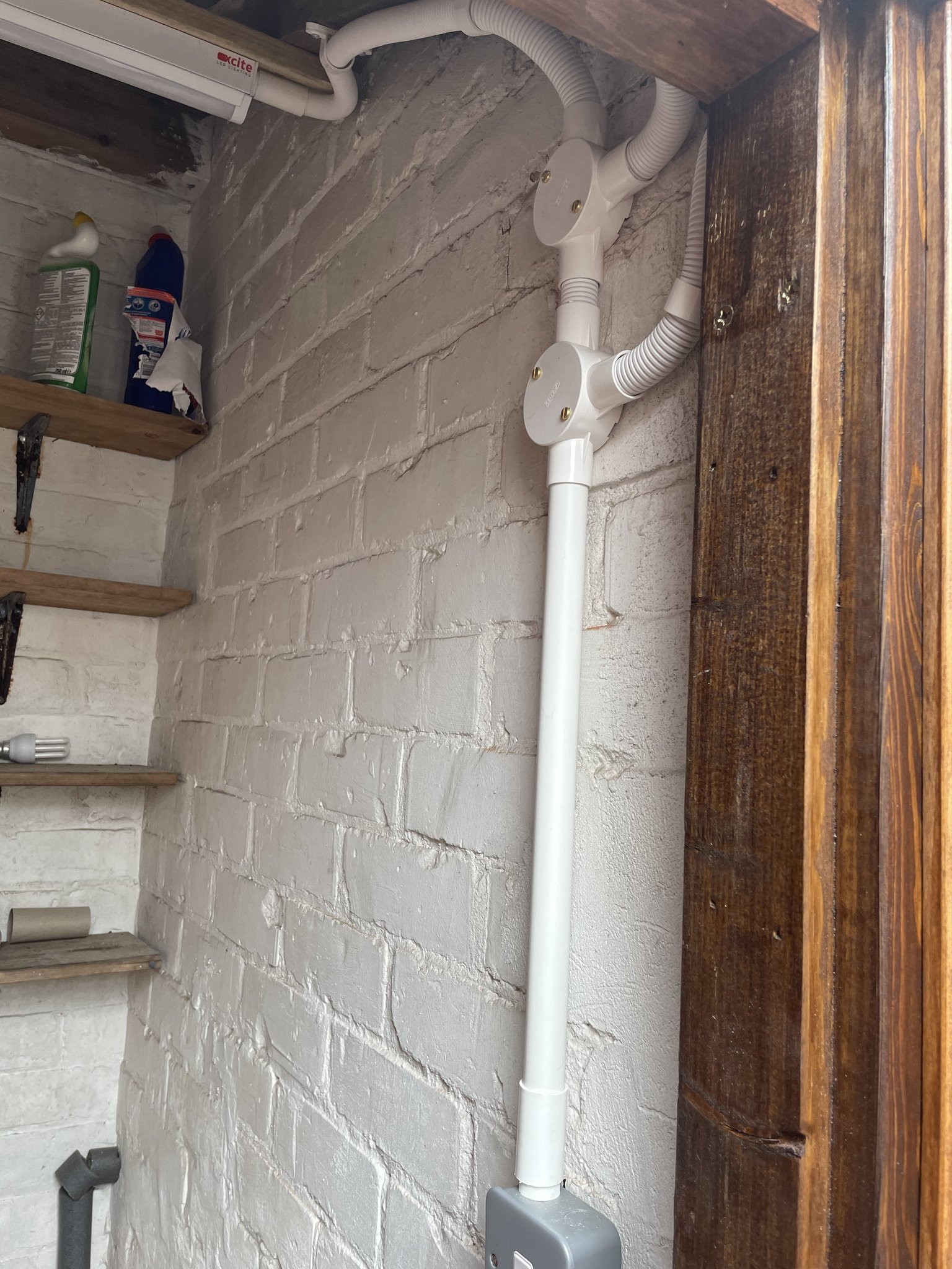 White conduit and a new fitting on a painted brick wall