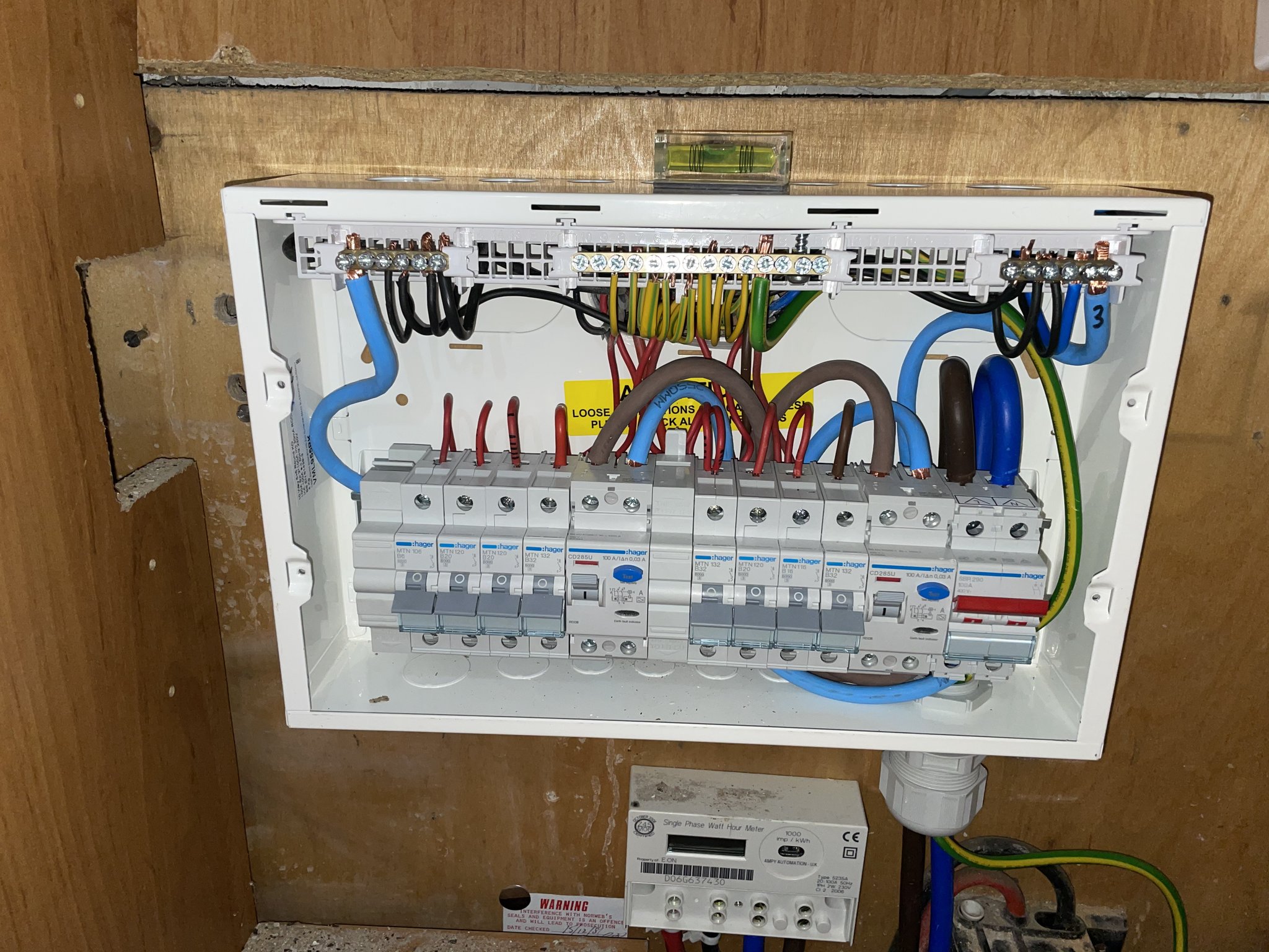 A new consumer unit fitted in a cupboard, cover open, circuits neatly dressed