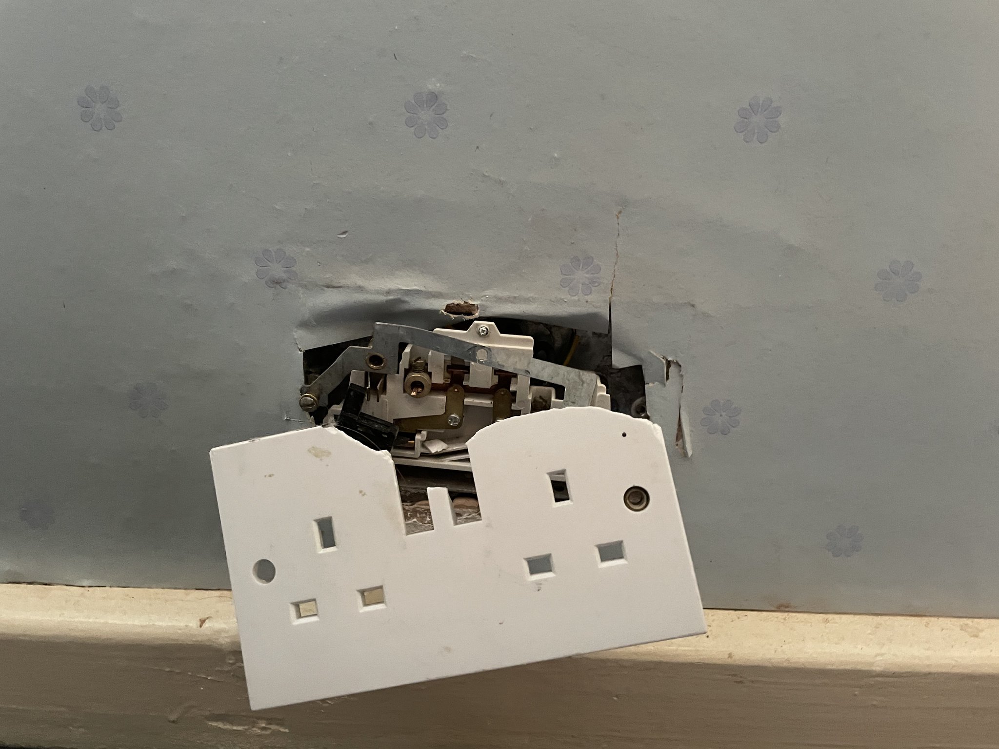 A broken double socket pulled away from the wall