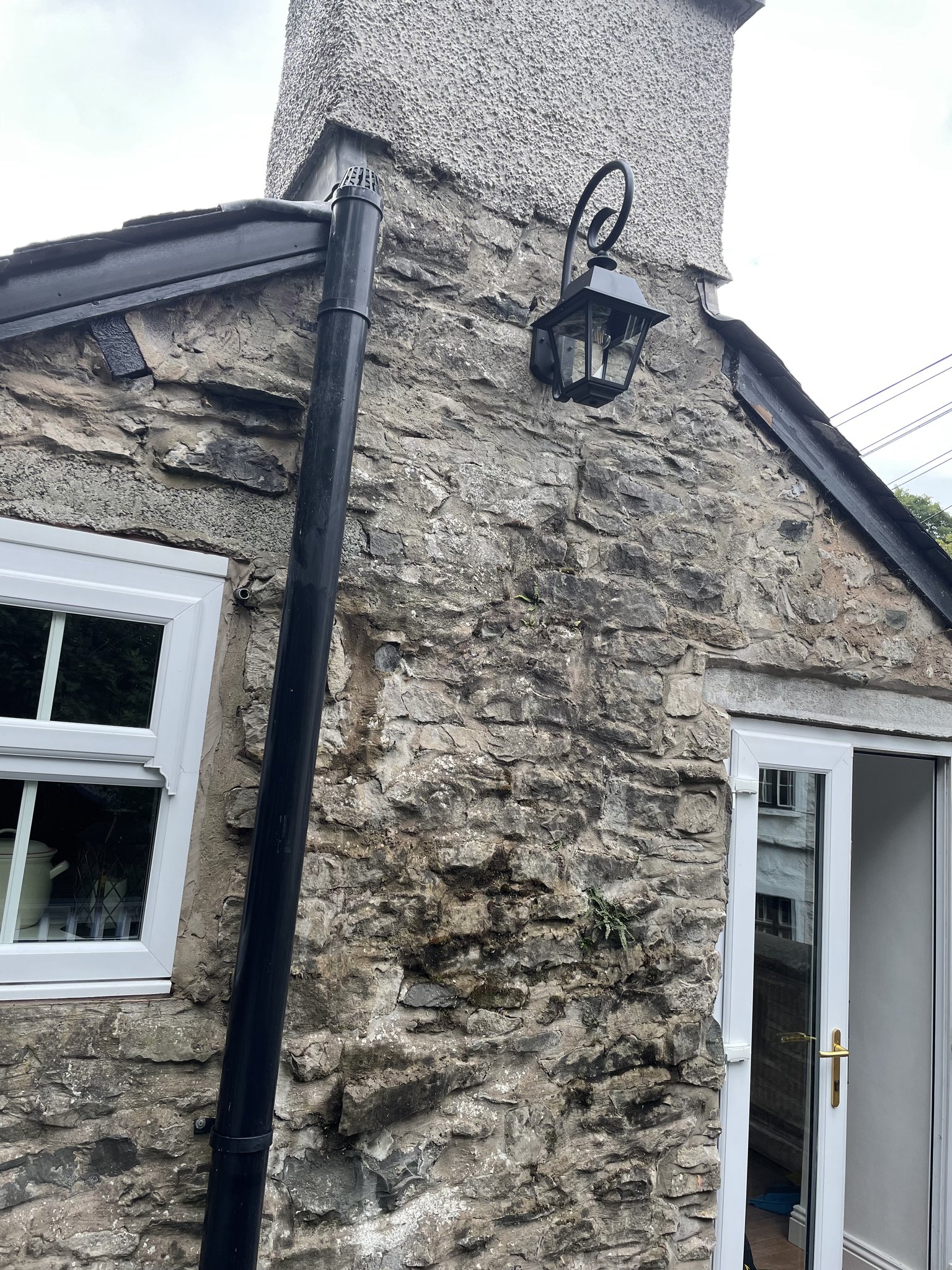 A black lantern fitted on the stone wall of a cottage