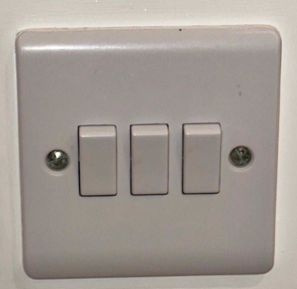 A new white triple light switch fitted flush to the wall